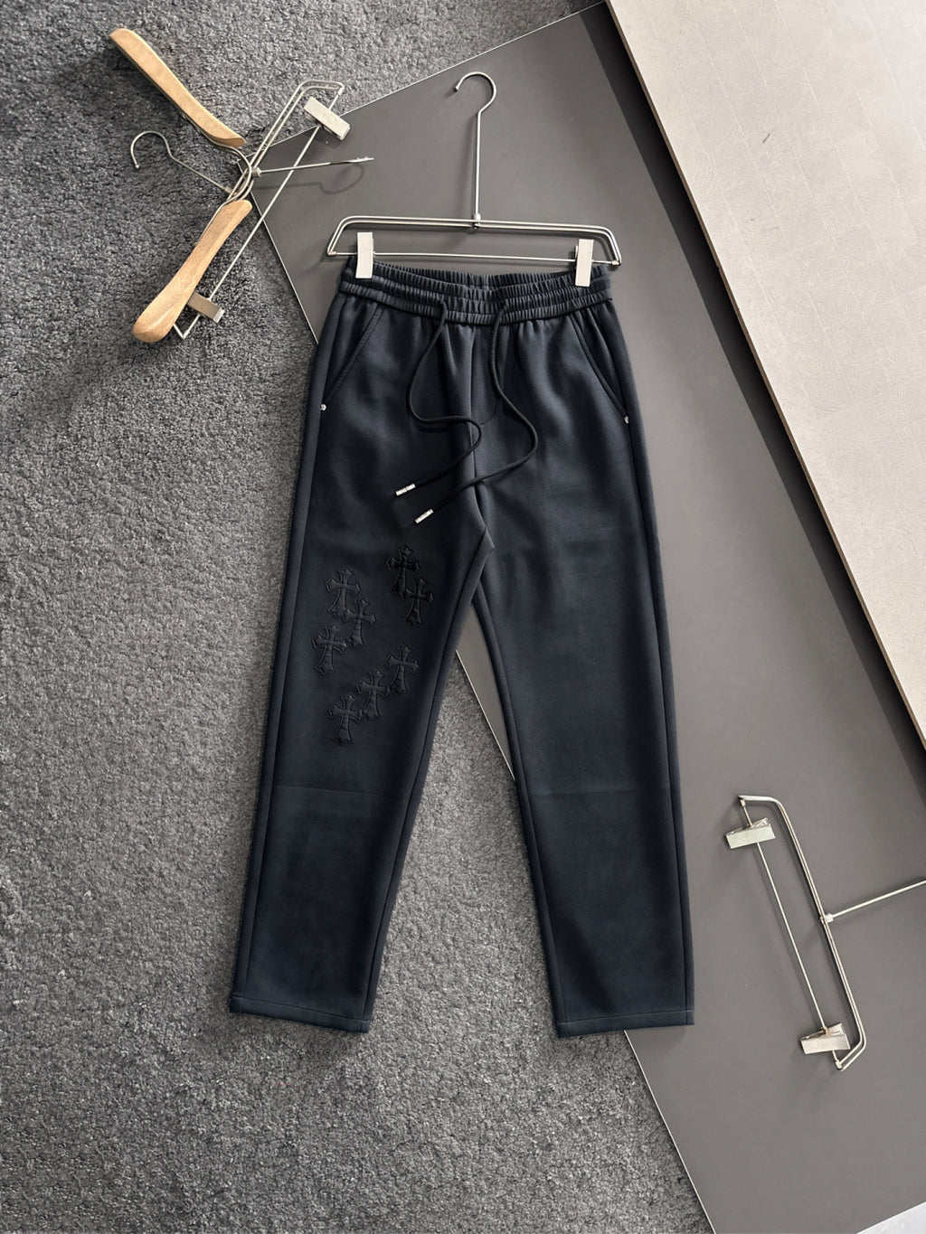 Dark pants with elastic waist, drawstring, side pockets, embroidered cross pattern