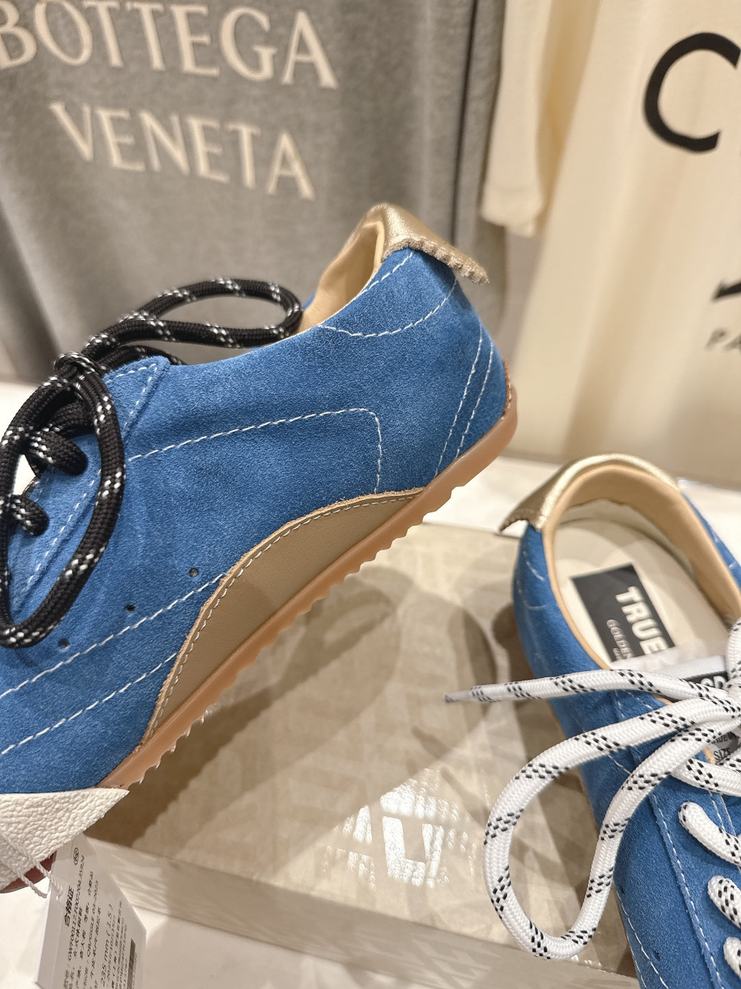 Blue sneaker close-up with black laces, beige lining, and stitched toe, gum sole