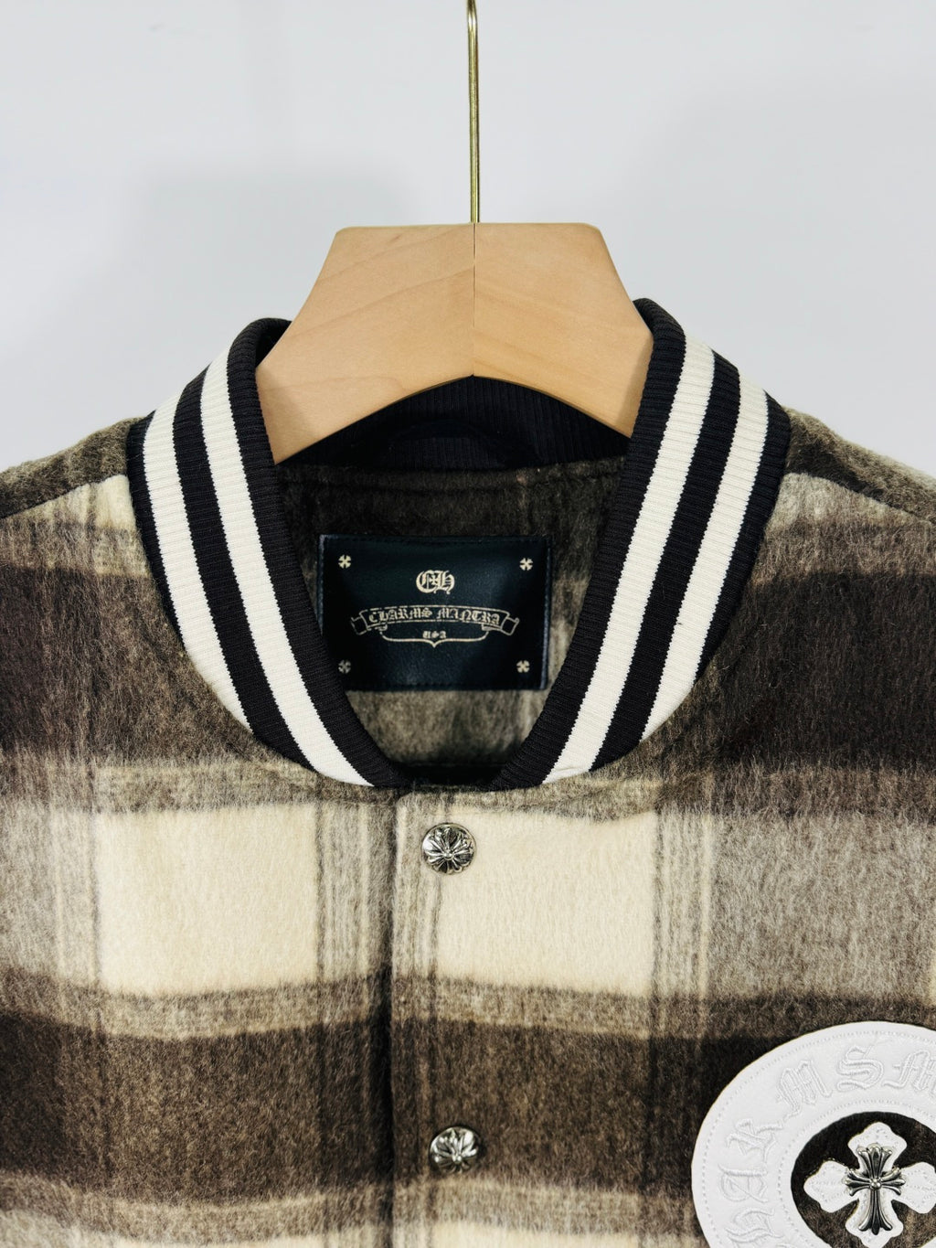 Plaid varsity jacket with striped ribbed collar and button placket, crest patch partially