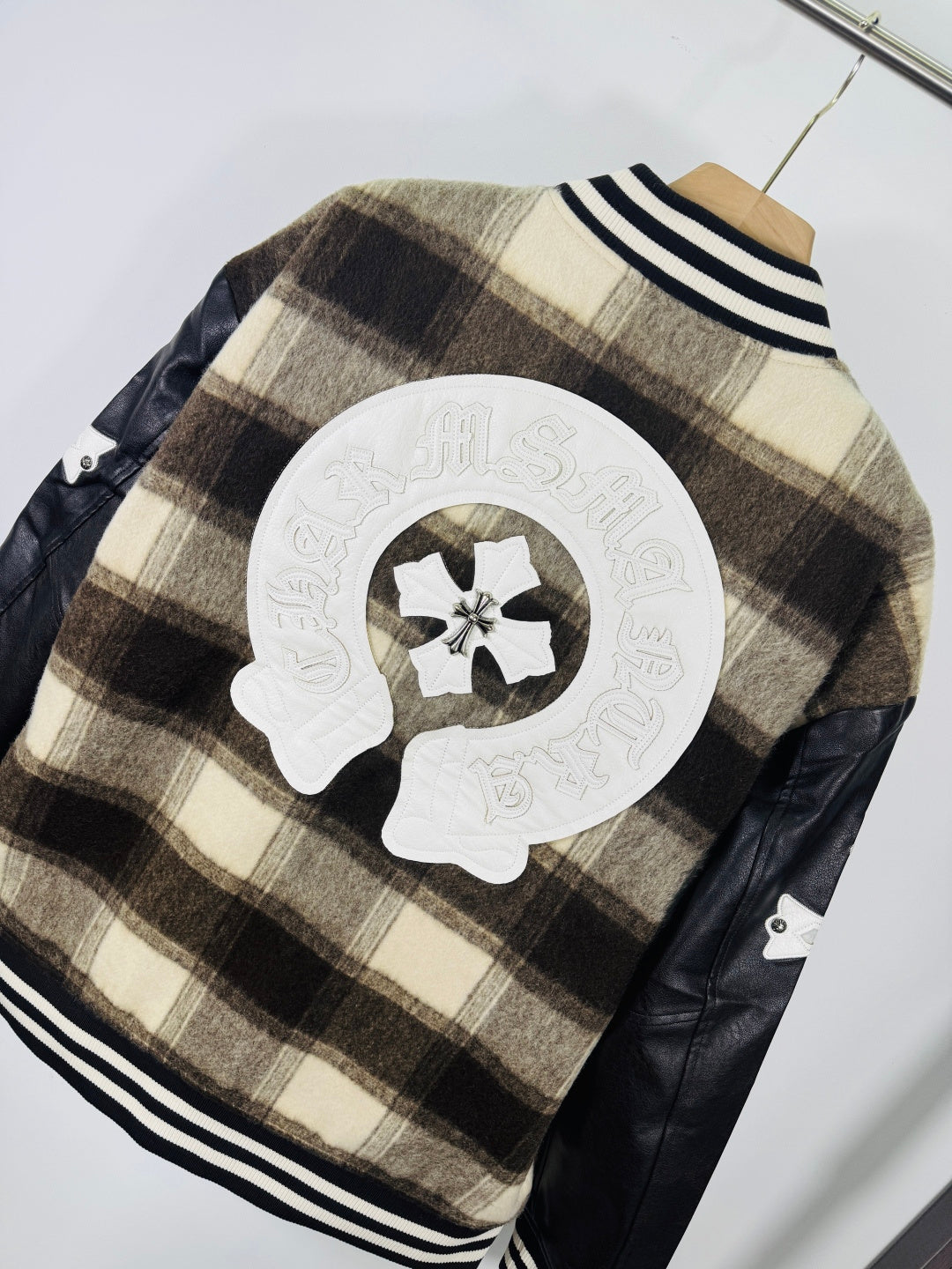Plaid varsity jacket back with oversized crest patch and black faux-leather side panels