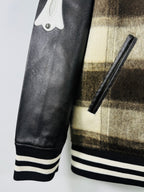 Black leather sleeve and ribbed striped cuff detail on plaid varsity jacket