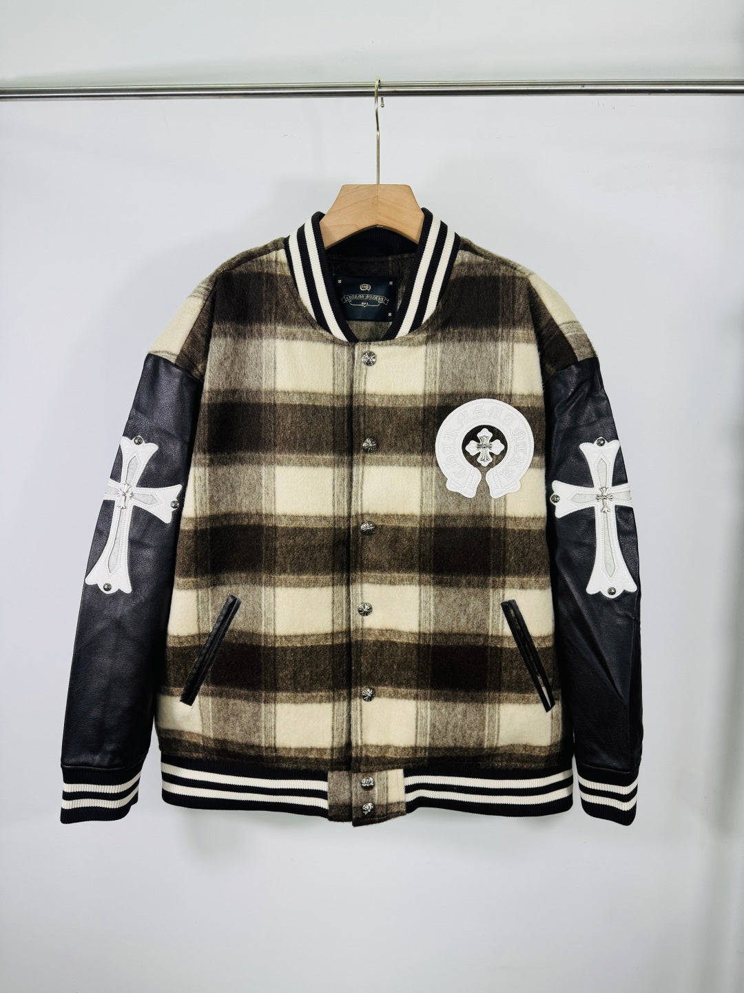 Plaid varsity jacket with black leather sleeves, striped ribbed collar and cuffs, chest patch