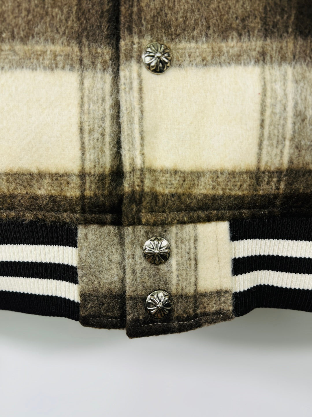Plaid varsity jacket front with metal buttons and striped ribbed hem