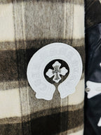 Close-up of plaid varsity jacket chest patch with white cross emblem on black-and-cream checks