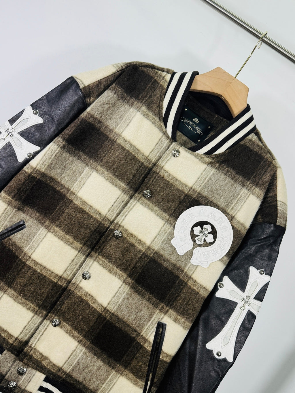 Plaid varsity jacket with crest patch and cross motifs on black sleeves