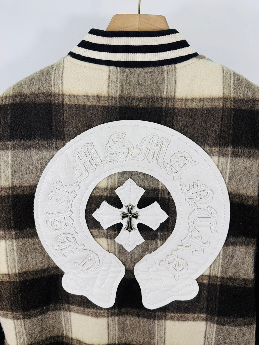 Large white cross-head patch on plaid jacket back with black emblem in center