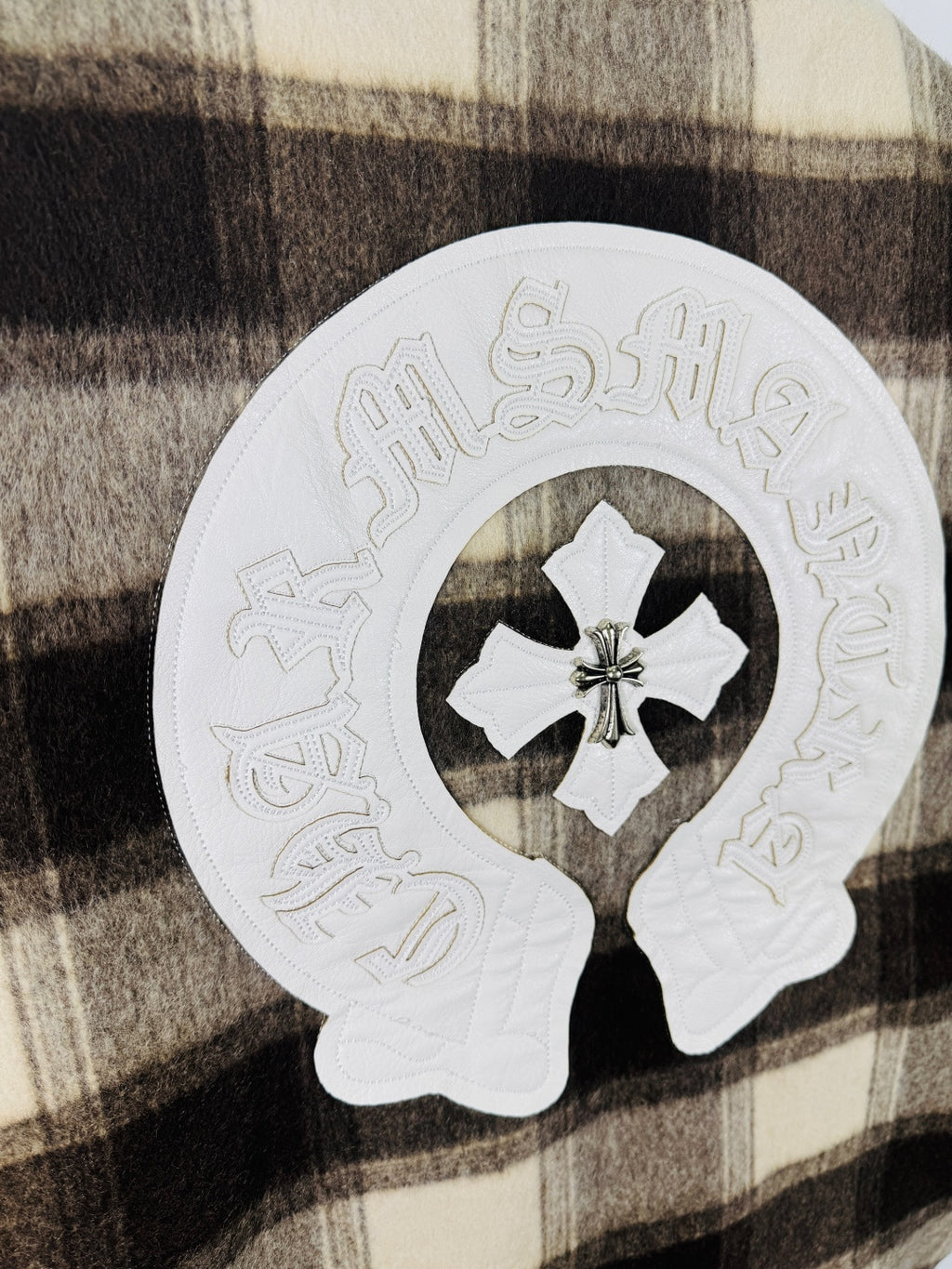 Embroidered circular patch with white stitched script and central four-petal flower