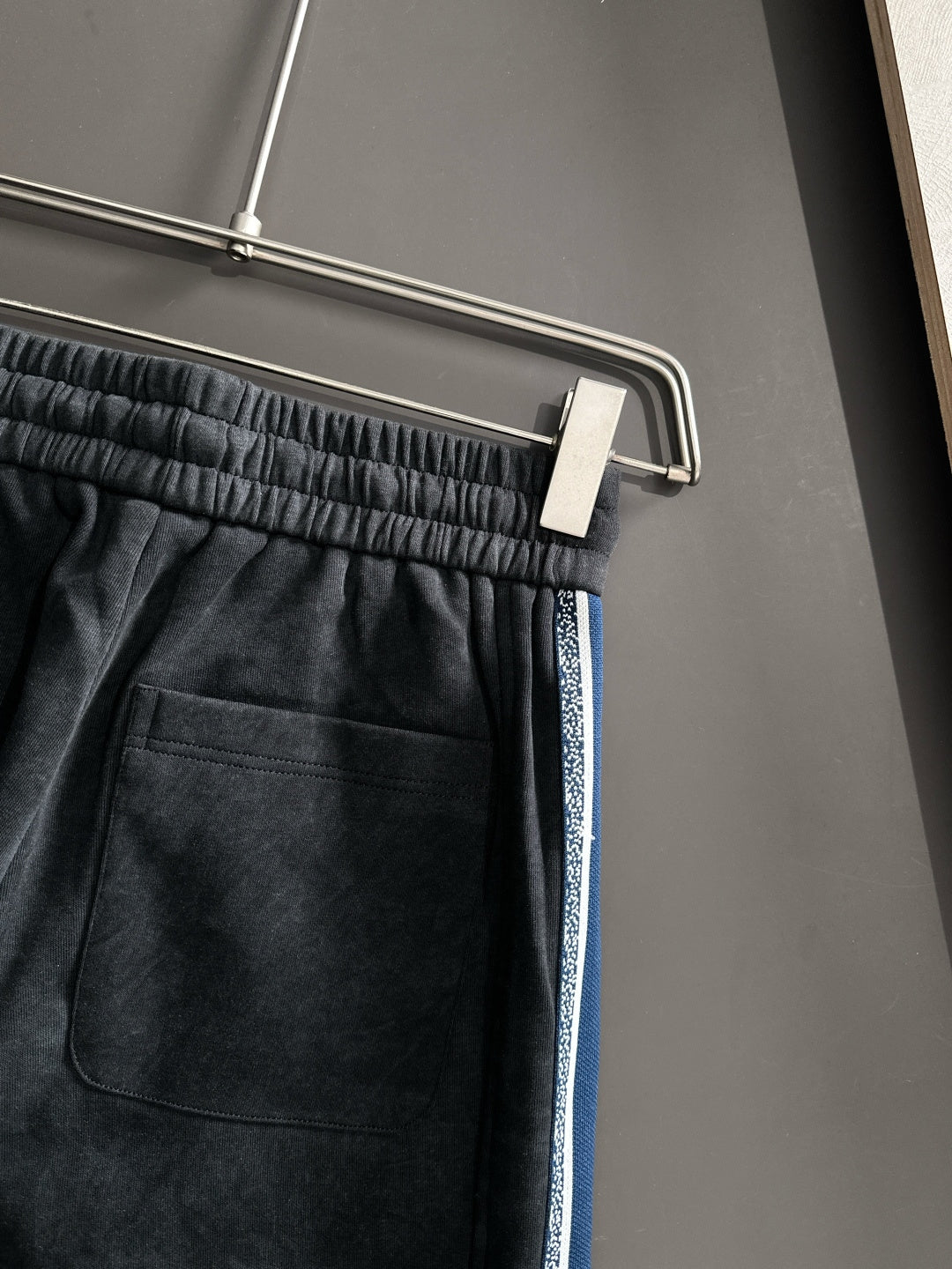 Dior pants front pocket area with elastic waistband and blue side stripe trim