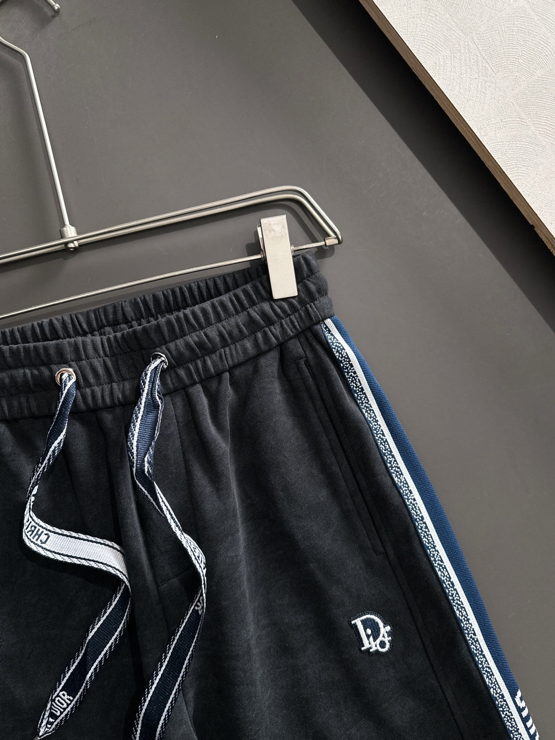 Dior pants close-up: elastic waistband with drawstring; dark fabric and blue trim stripe