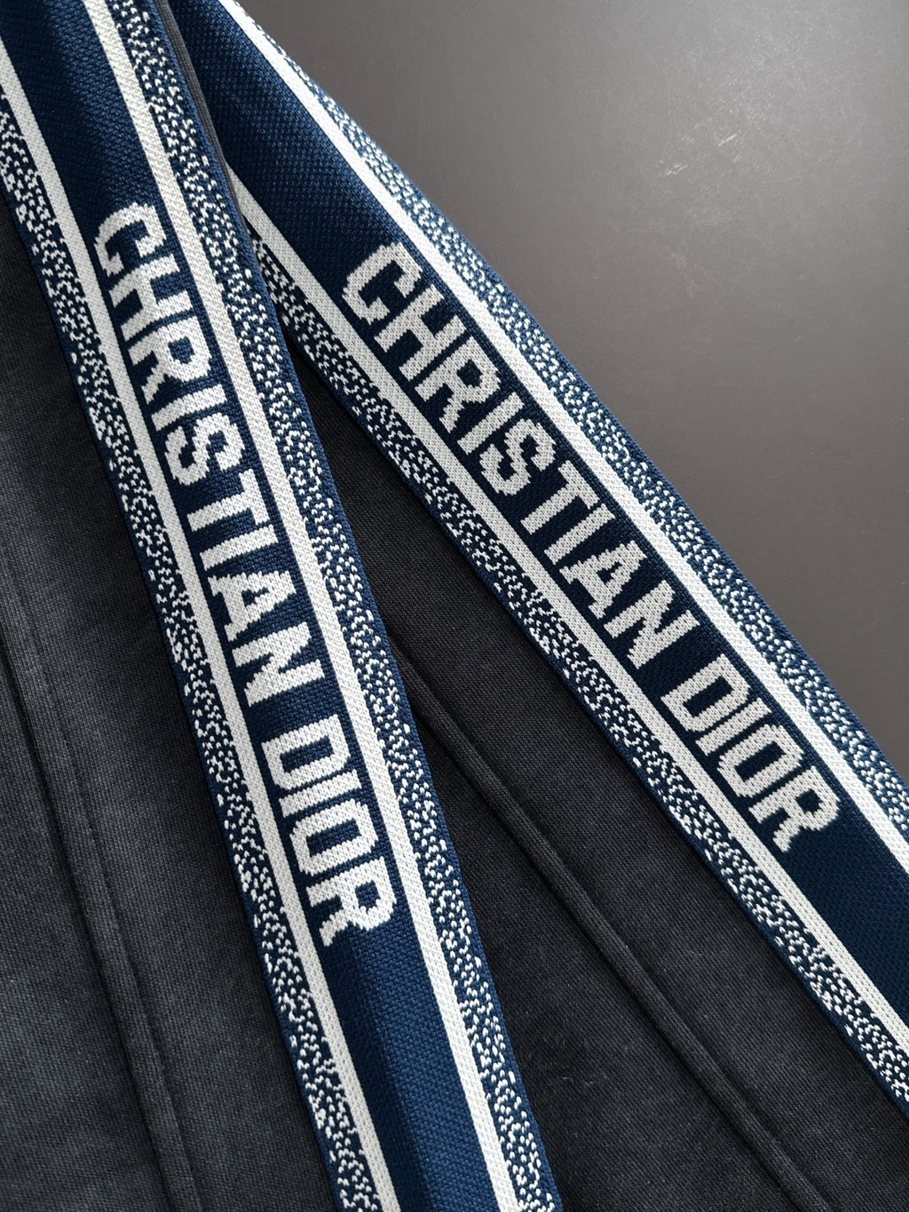 Dior pants side stripe detail with repeating logo text on blue and white trim