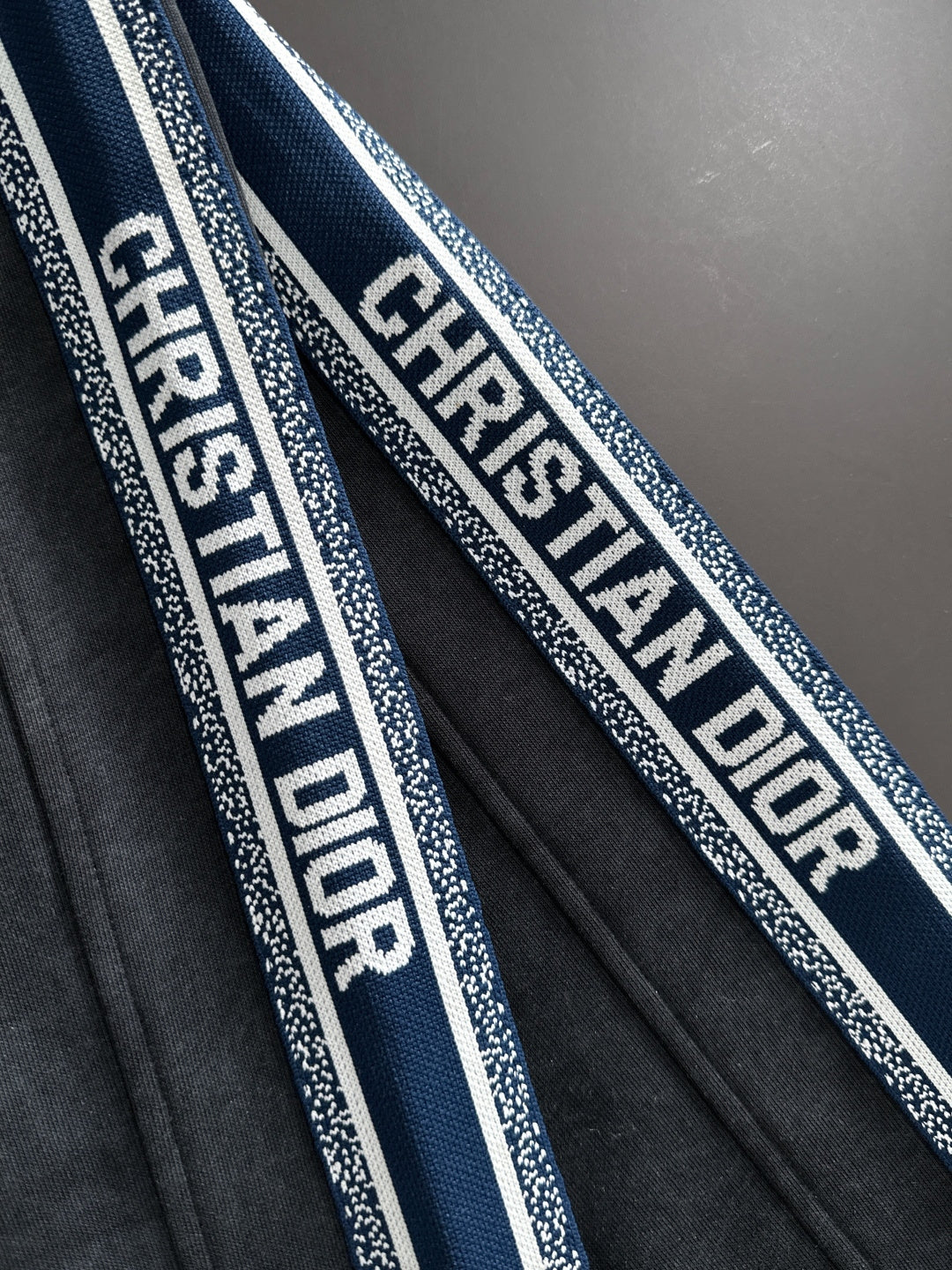 Dior pants side stripe detail with repeating logo text on blue and white trim
