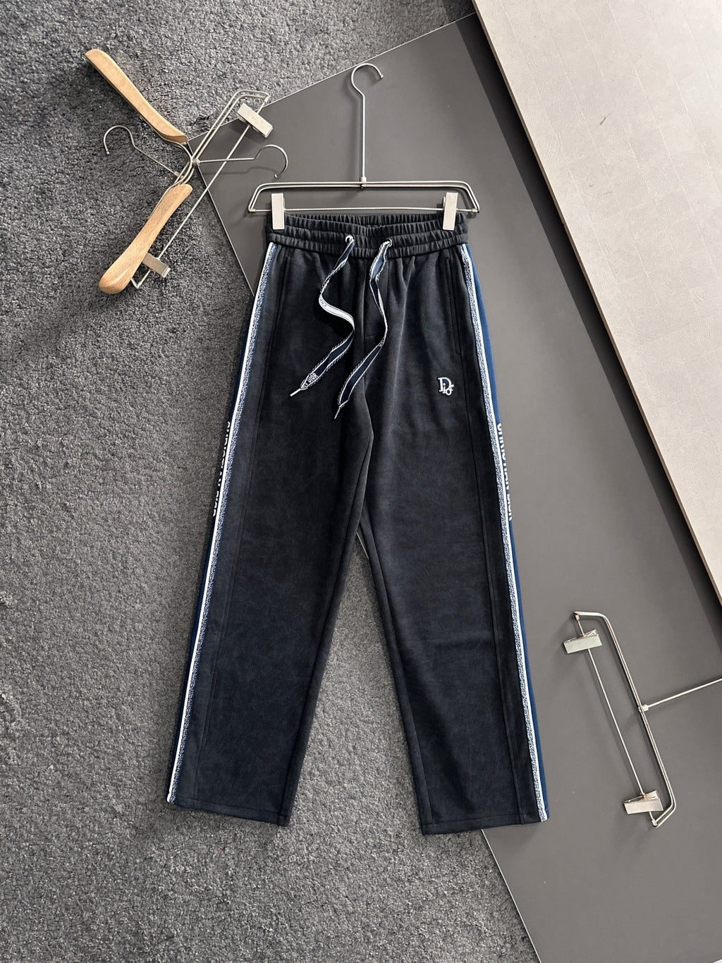 Dior pants in dark fabric with elastic waist, drawstring, and blue side stripes
