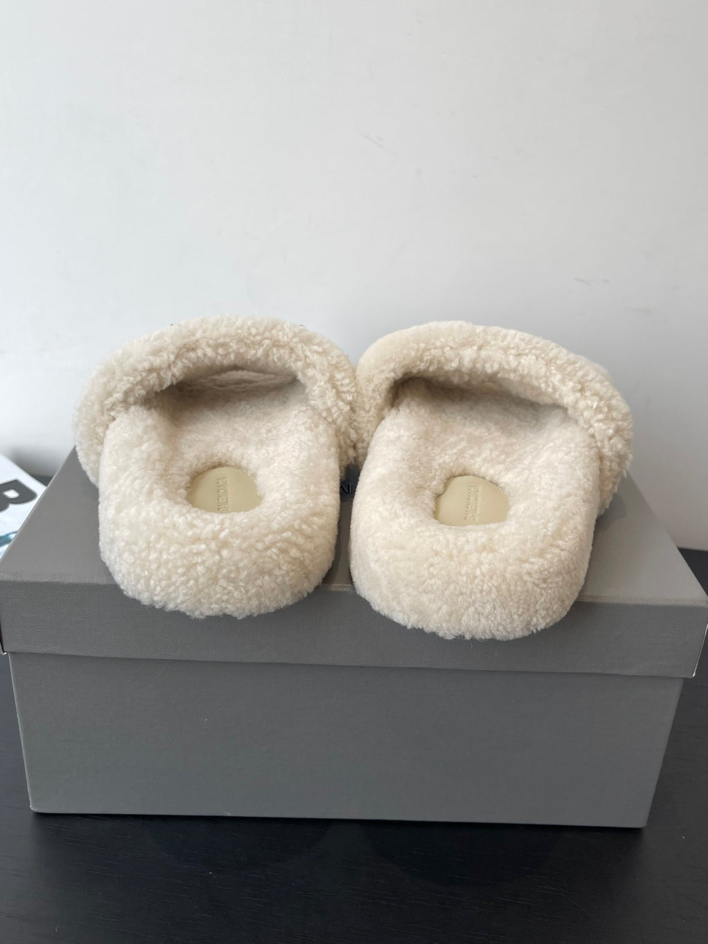 Pair of beige shearling slide sandals with open oval toe, front view