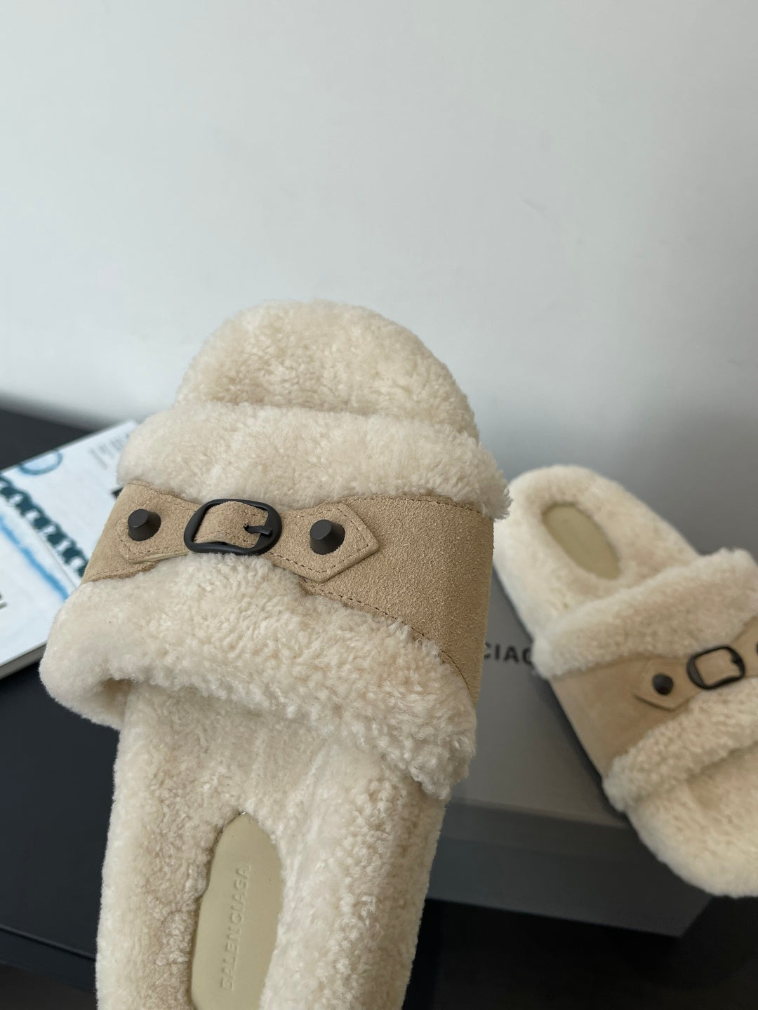 Beige shearling slide sandal with top strap and metal buckle, side view