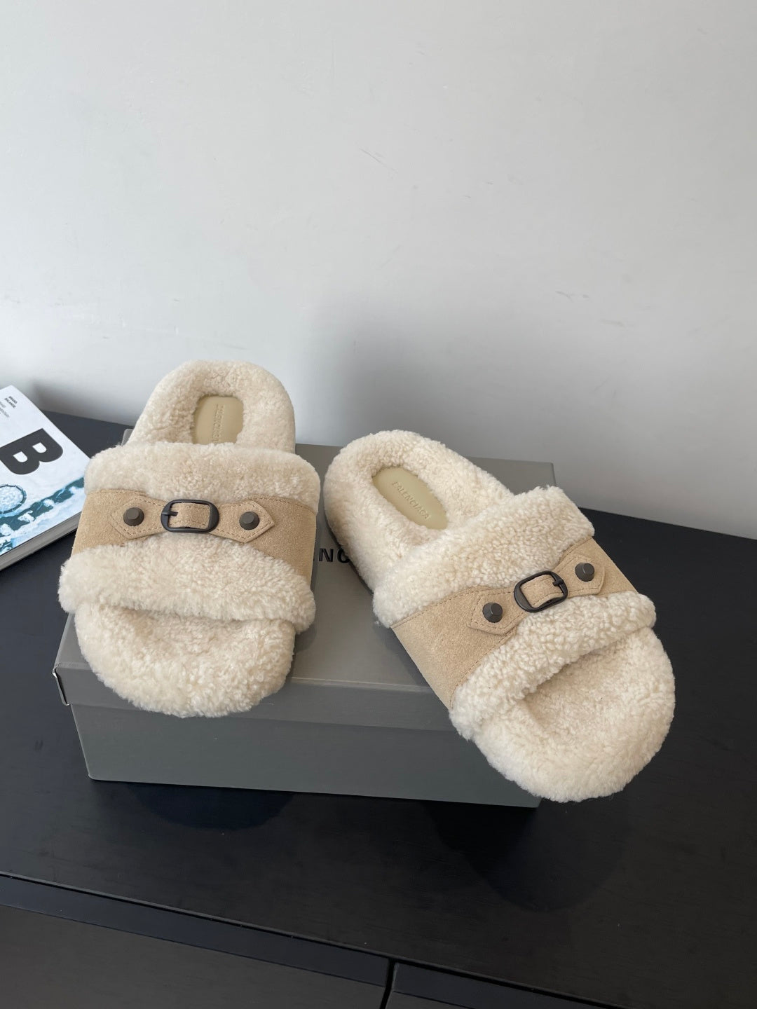 Beige shearling slide sandals with buckled strap, angled front view