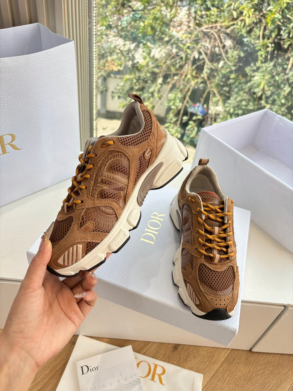 Brown lace-up sneakers in hand, chunky white sole with tan laces