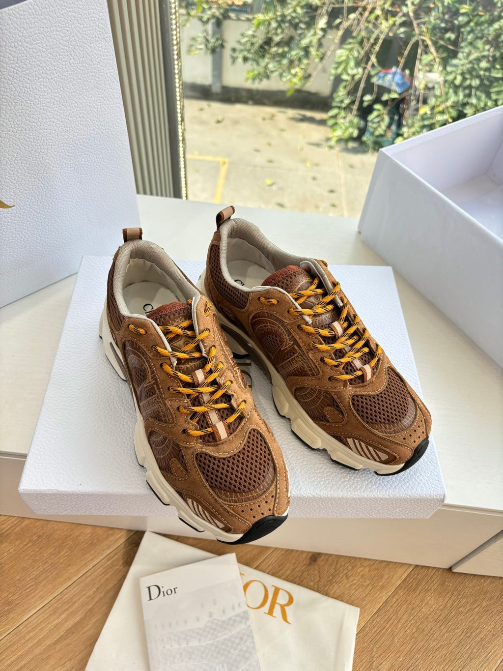 Brown lace-up sneakers on white box, front angle, gold laces and cushioned collar