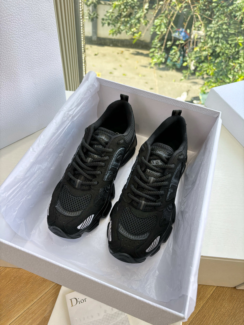 Black lace-up sneakers in a box with black mesh and cushioned sole