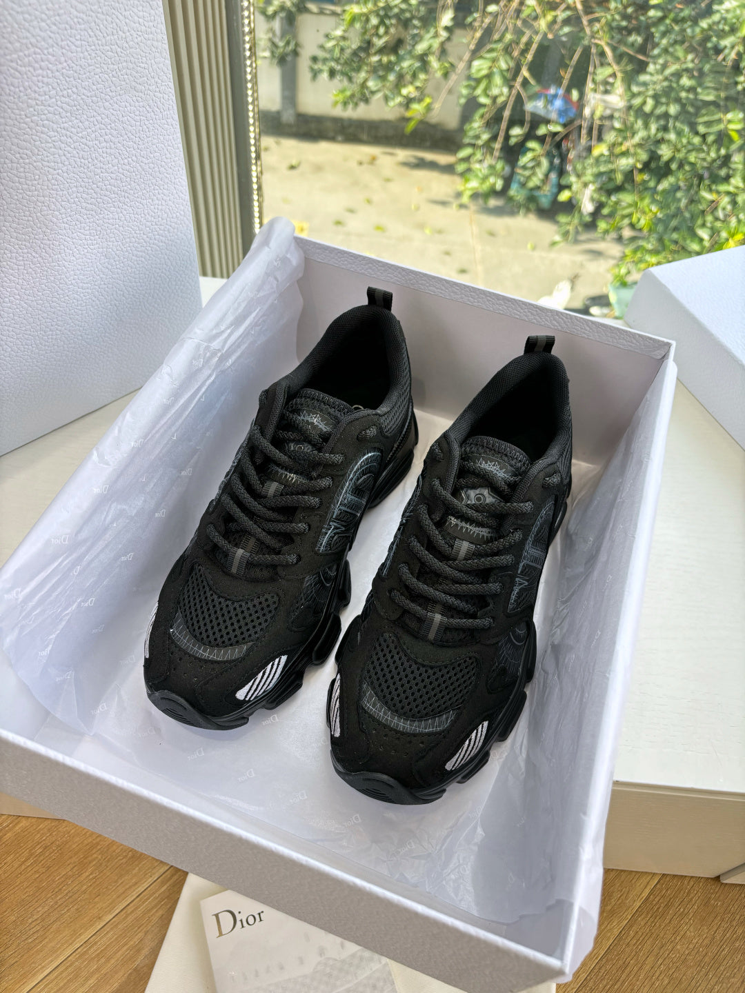 Black lace-up sneakers in a box with black mesh and cushioned sole