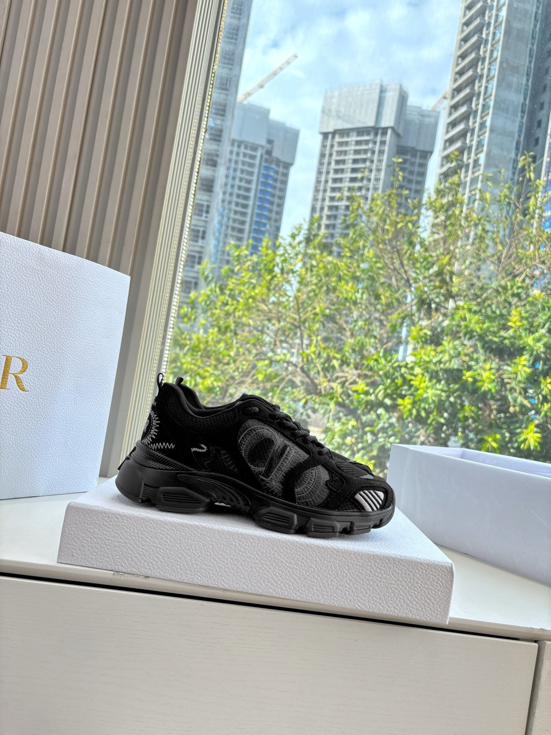 Black lace-up sneaker sitting on a shoebox ledge