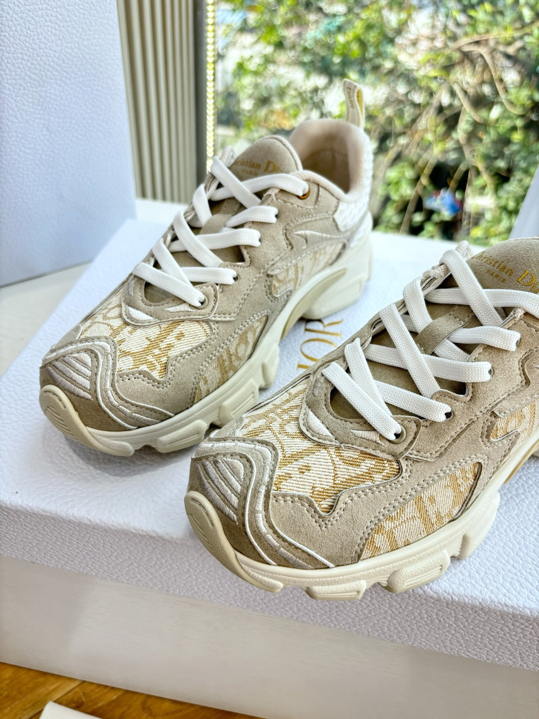 Close-up of beige lace-up sneakers with white laces and logo pattern