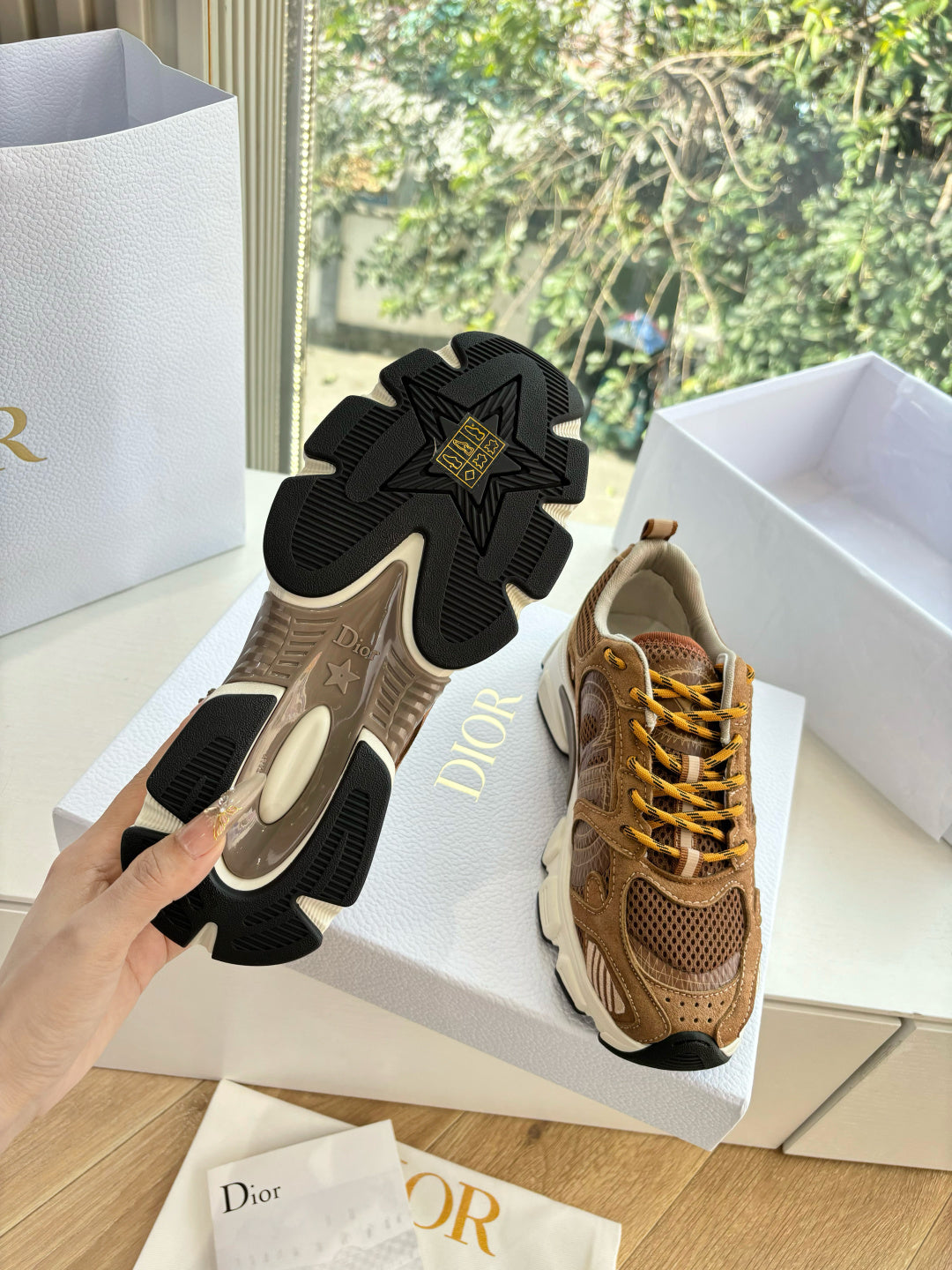 Brown sneakers with black tread outsole view and star logo on cream midsole