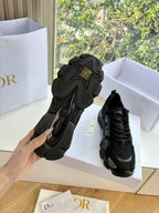 Black sneakers showing outsoles and heels, pair in white shoe boxes