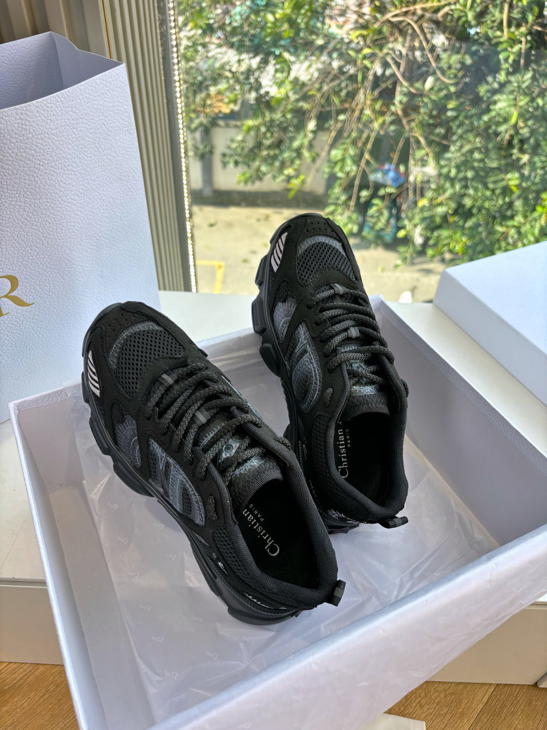 Pair of black lace-up sneakers angled in a white shoe box