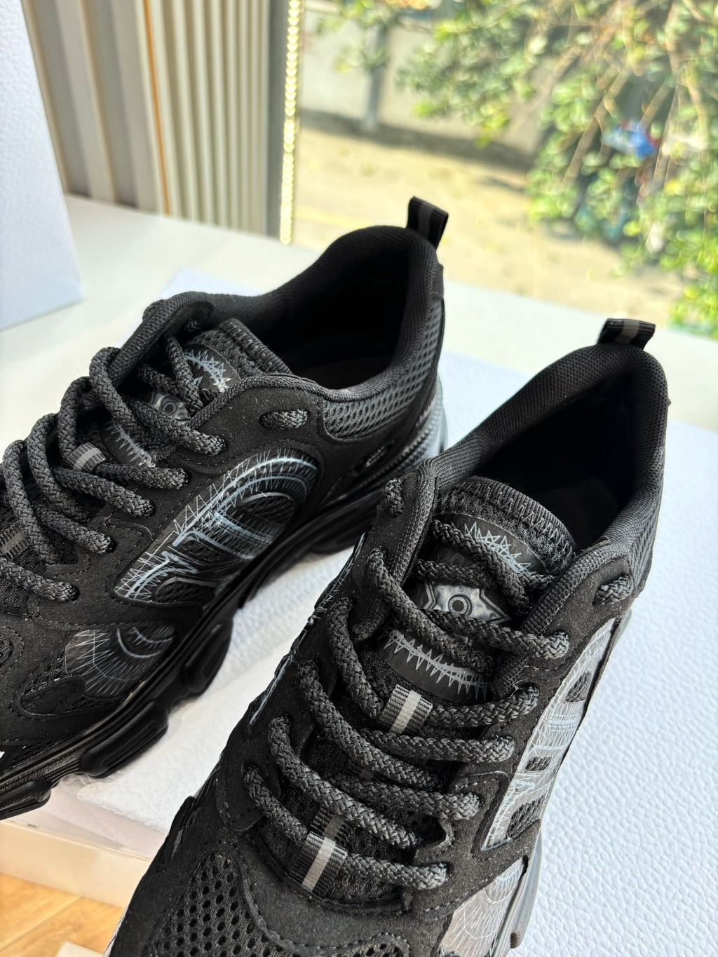 Close-up of black lace-up sneakers with textured panels and patterned laces