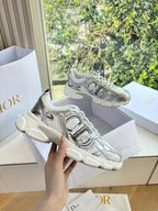 Ladies' gray lace-up sneakers with mesh uppers and cushioned sole, held up