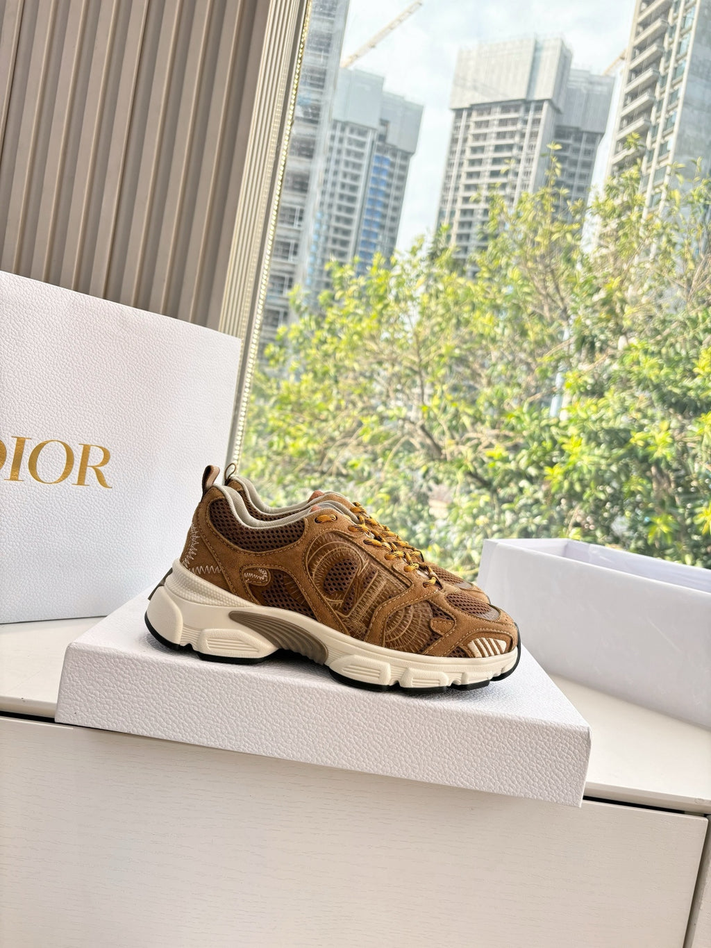 Brown lace-up sneakers on display box, sporty knit upper and white midsole