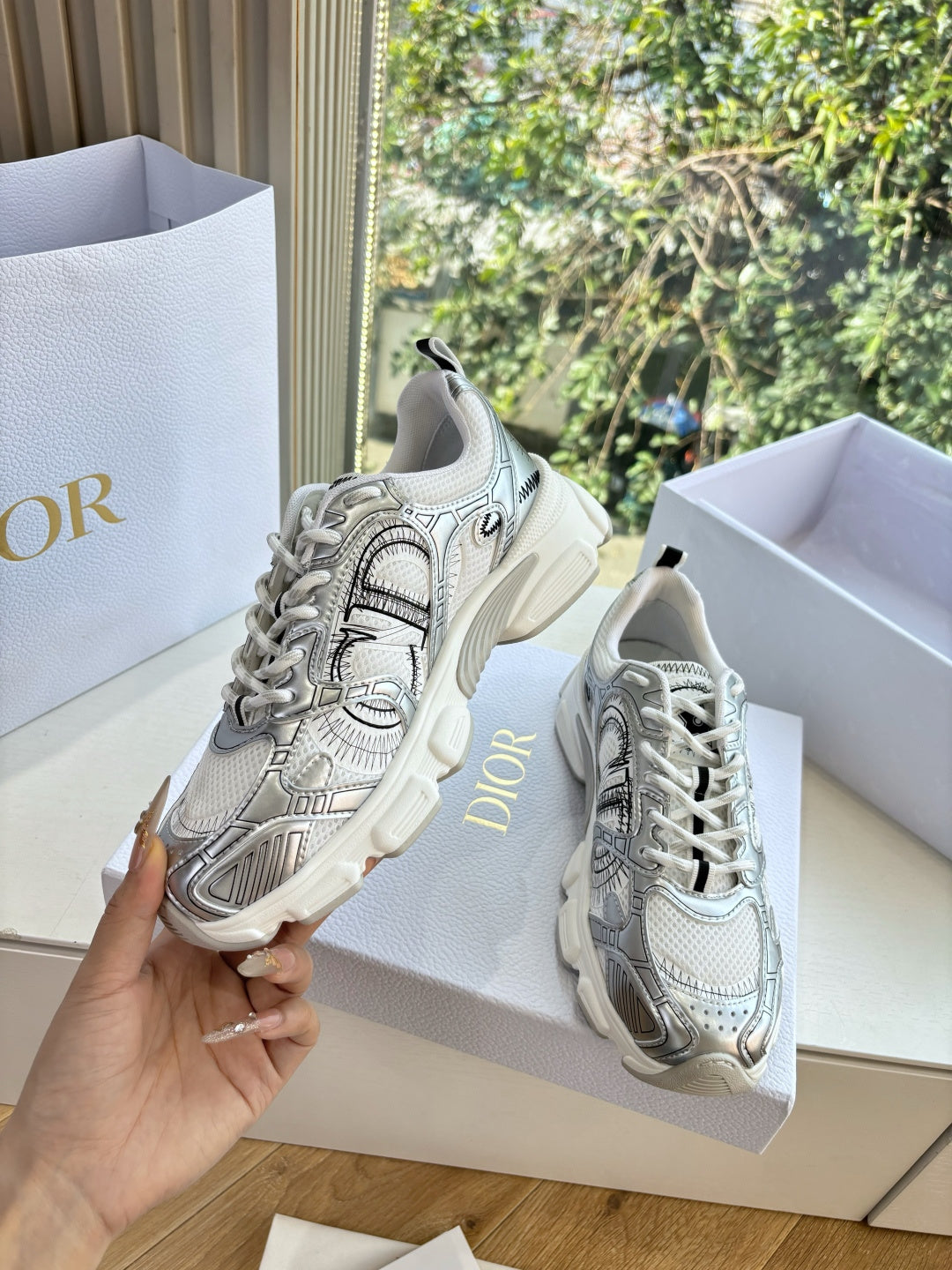 Ladies' gray lace-up sneakers with textured details, held in one hand