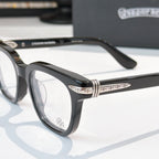 Black eyeglasses close-up with patterned temples and clear front lenses.