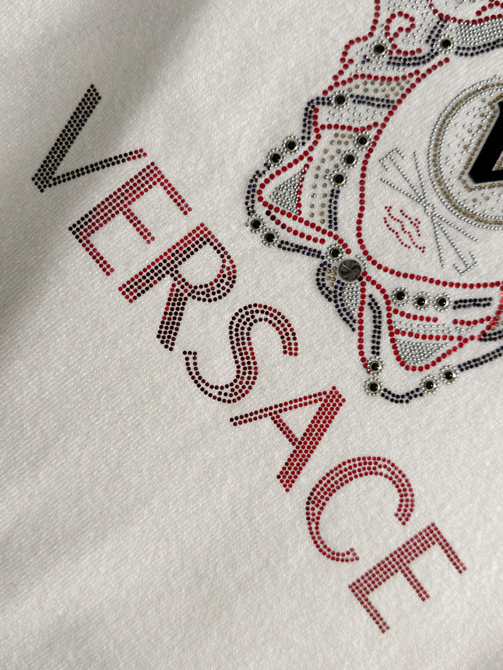 White Versace sweatshirt sleeve close-up with rhinestone lettering and part of dog graphic