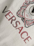 White Versace sweatshirt sleeve close-up with rhinestone lettering and part of dog graphic