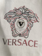 White Versace sweatshirt close-up of rhinestone dog emblem and VERSACE logo text