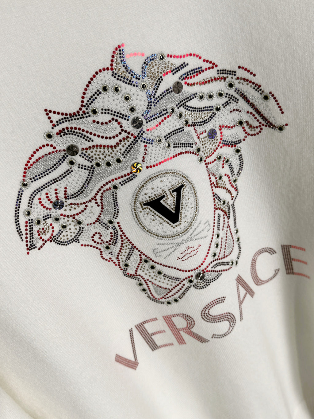 White Versace sweatshirt chest close-up of rhinestone dog emblem with VERSACE text