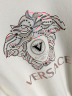 White Versace sweatshirt chest close-up of rhinestone dog emblem with VERSACE text