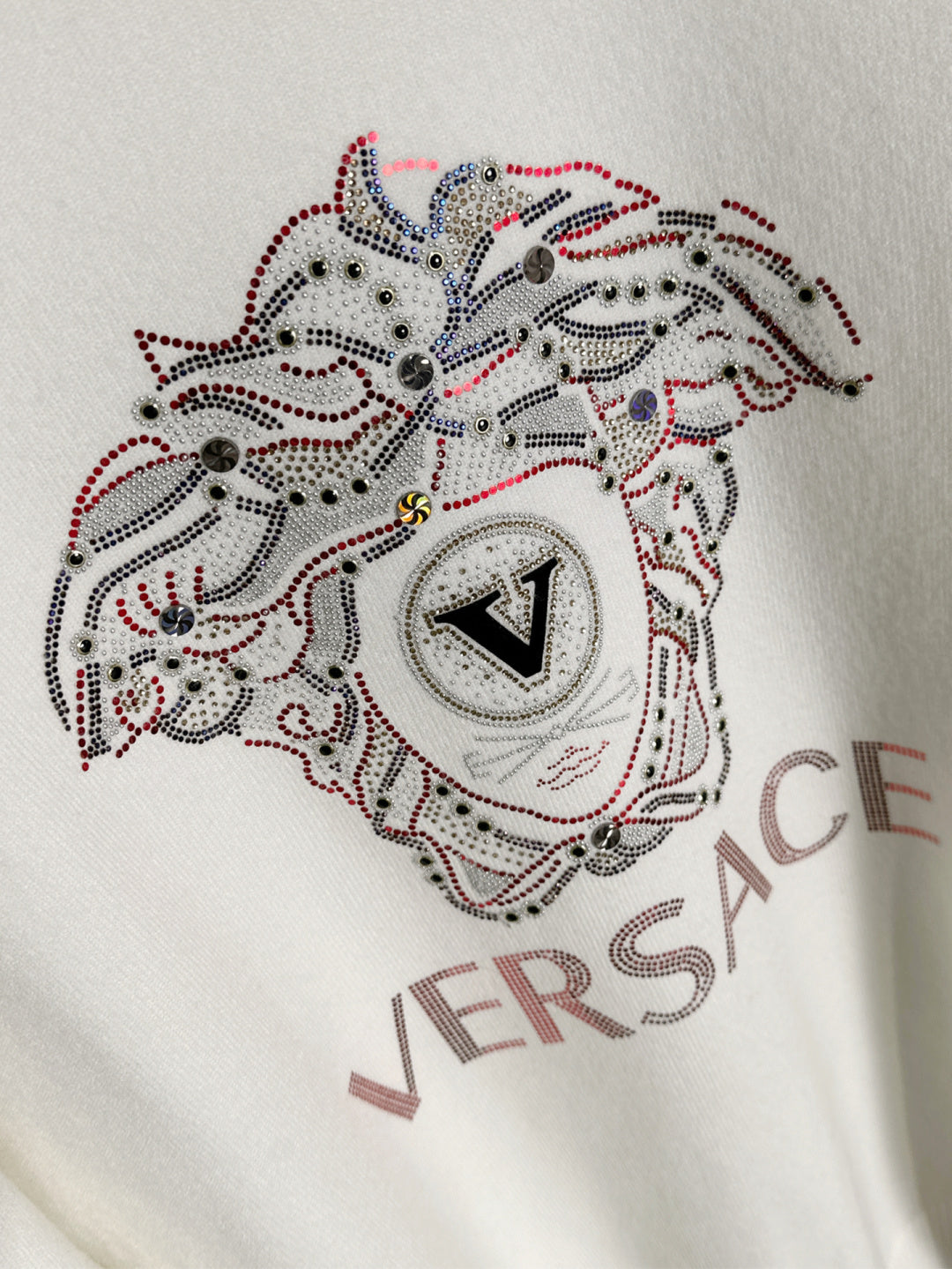 White Versace sweatshirt chest close-up of rhinestone dog emblem with VERSACE text