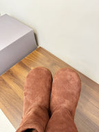 Brown suede ankle boots worn-looking, close-up of two boots on wooden floor