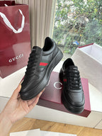 Gucci women's black leather sneakers, lace-up pair held in hand