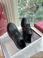 Gucci women's black leather sneakers pair, lace-up style with side stripe accents