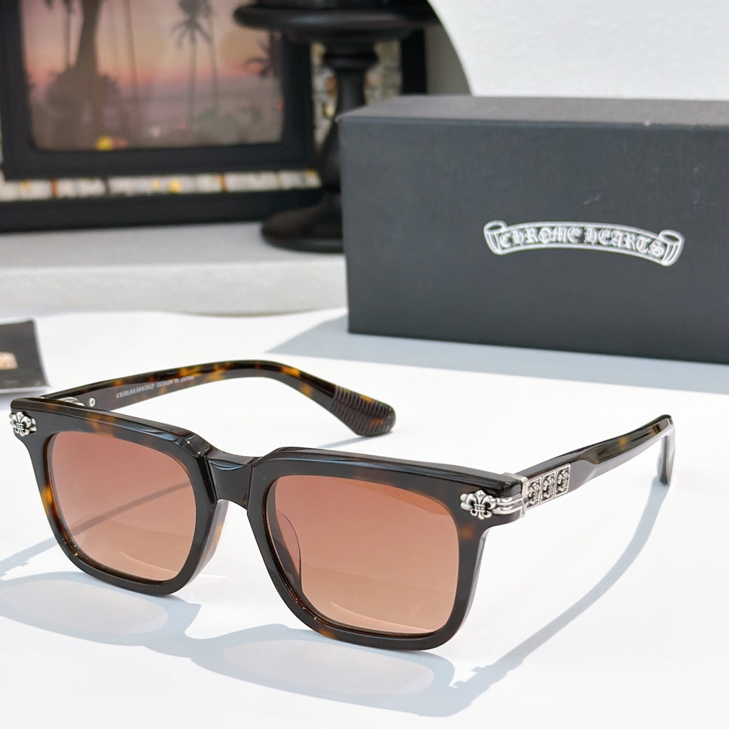 Sunglasses with brown-tinted lenses, black frame, and silver ornate temple details.