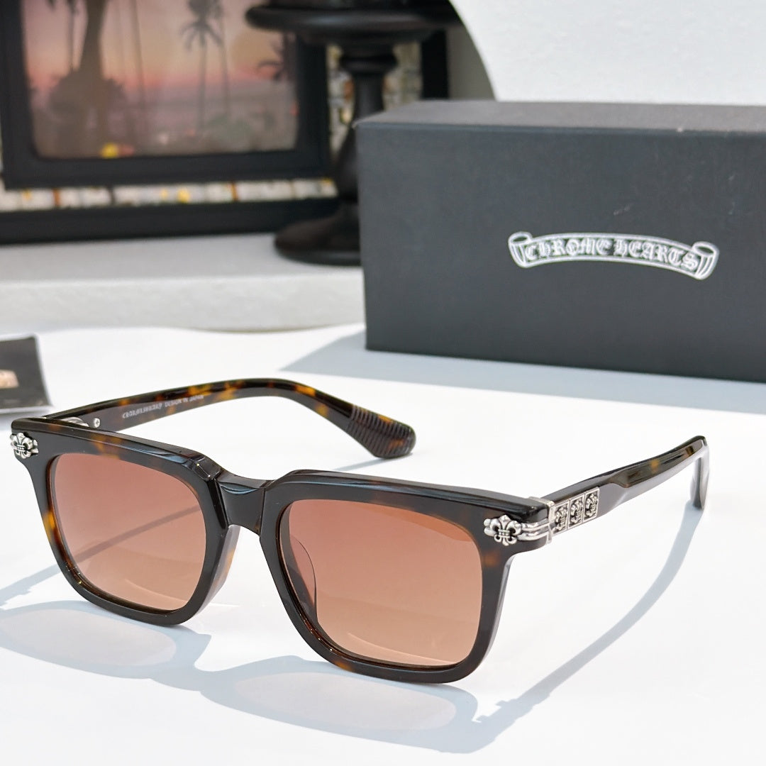 Sunglasses with brown-tinted lenses, black frame, and silver ornate temple details.