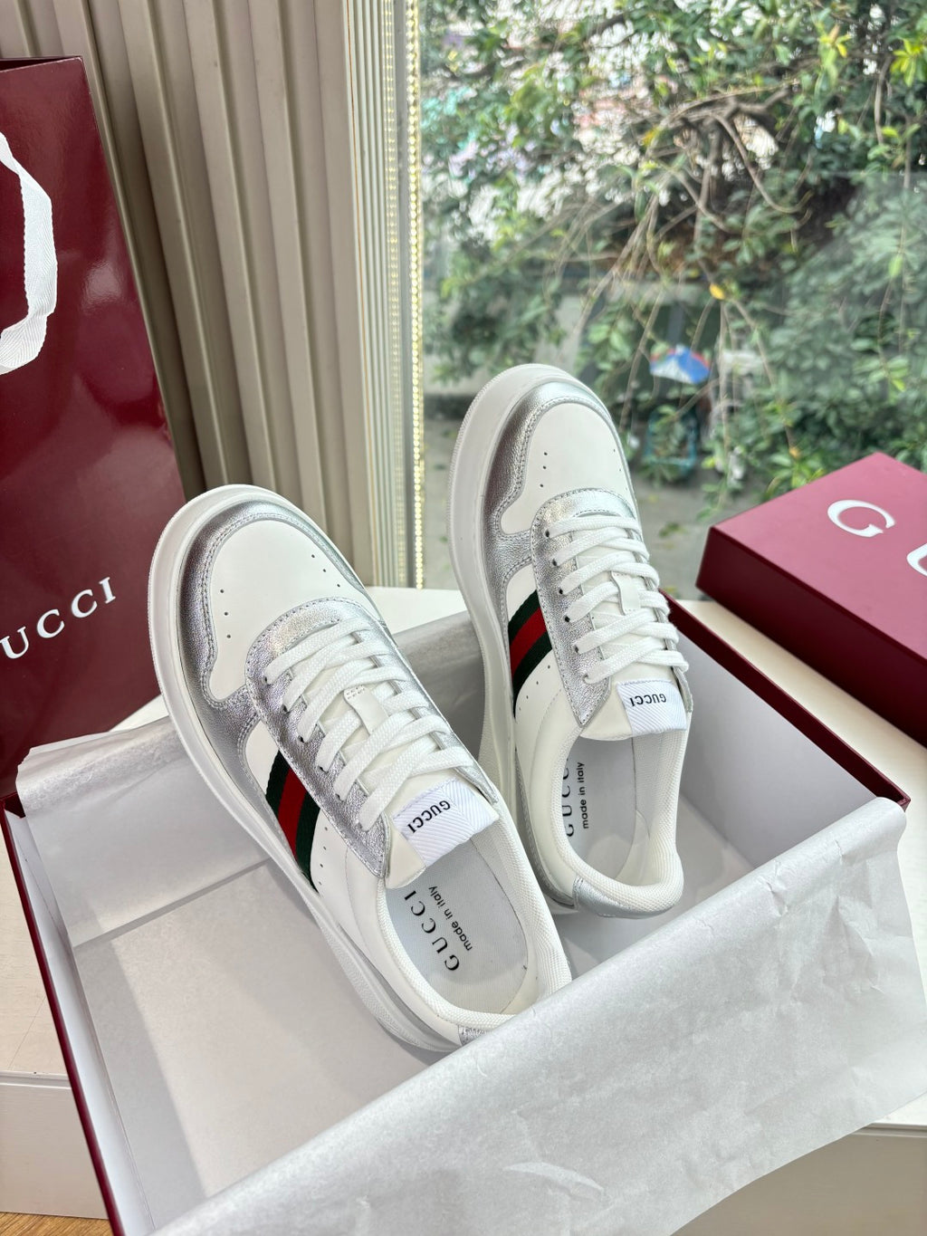 White Gucci leather sneakers, side profile with red and green stripe and lace-up front