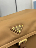Close-up of tan flap with rectangular logo patch and gold border hardware