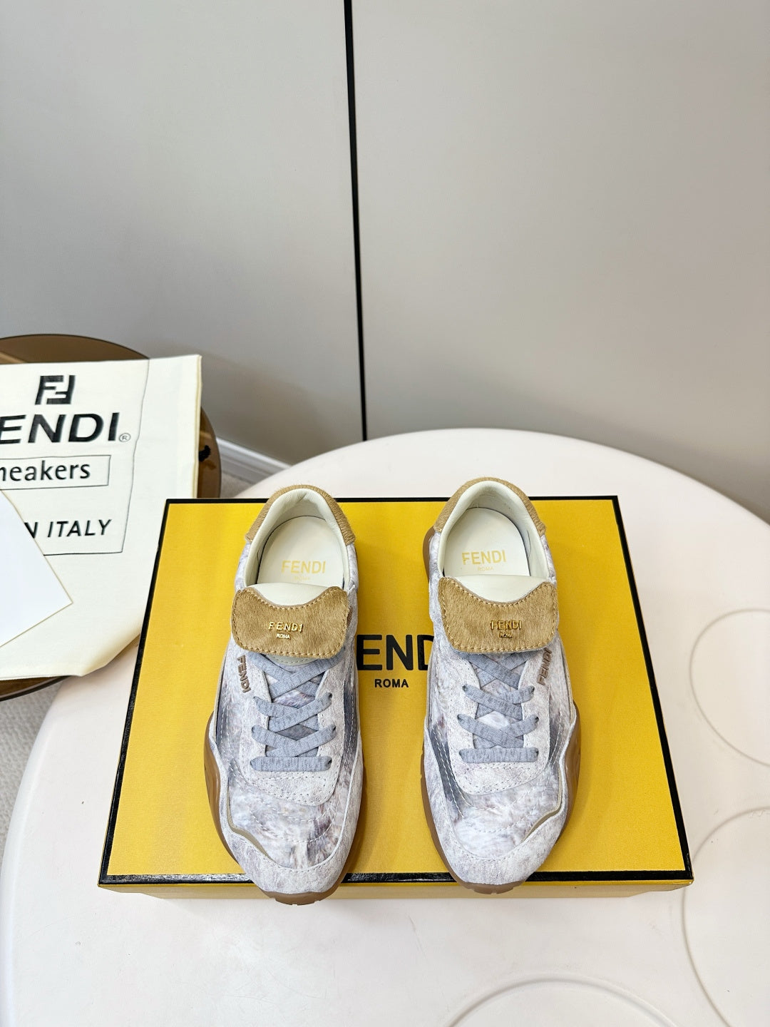 Fendi unisex sneakers in light gray with tan suede heel tabs and lace-up fronts.