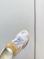 Fendi unisex sneaker close-up, tan heel tab and light gray lace-up upper.