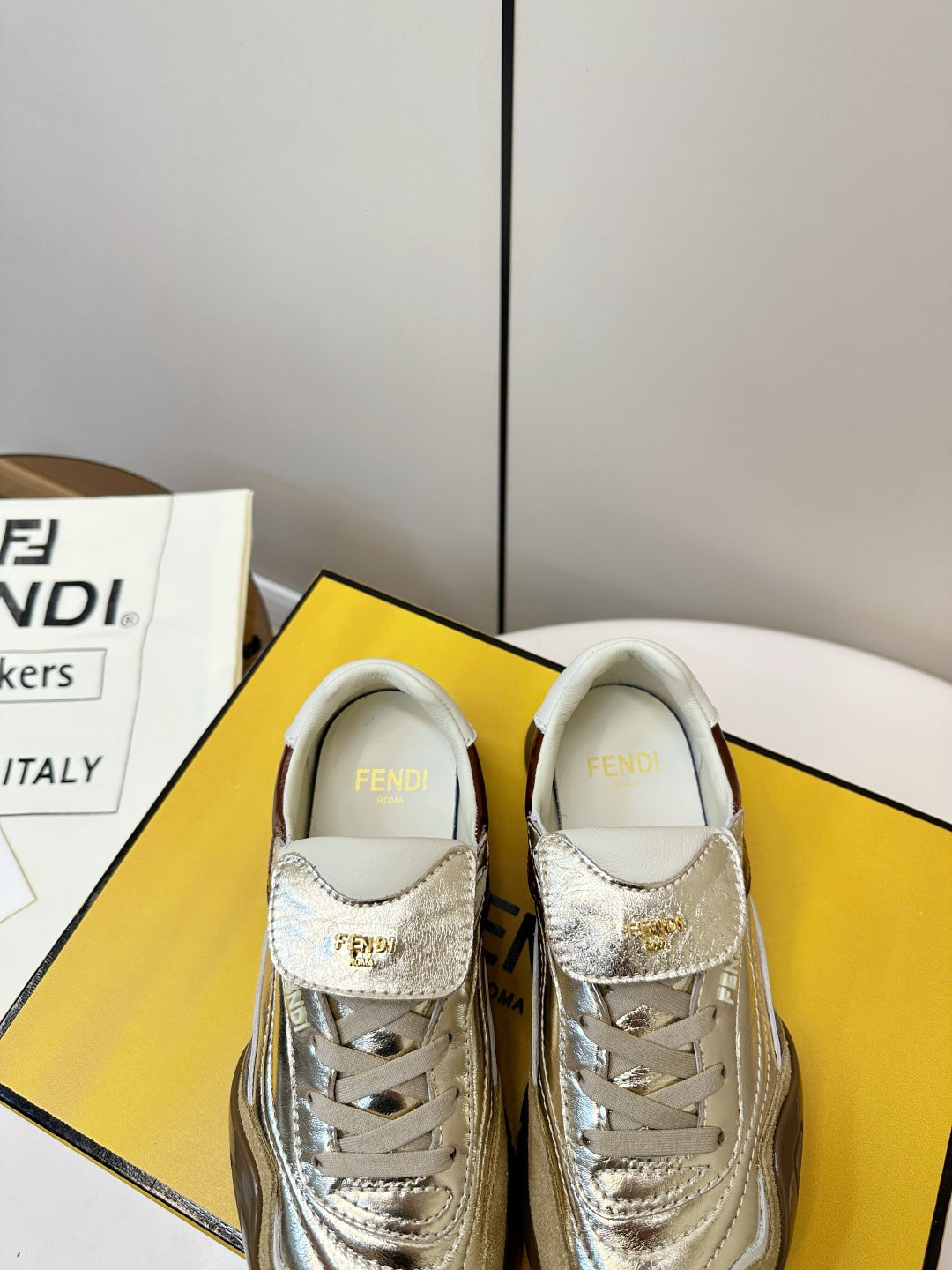 Fendi unisex sneakers front view, metallic gold uppers with brown heel tab and white laces