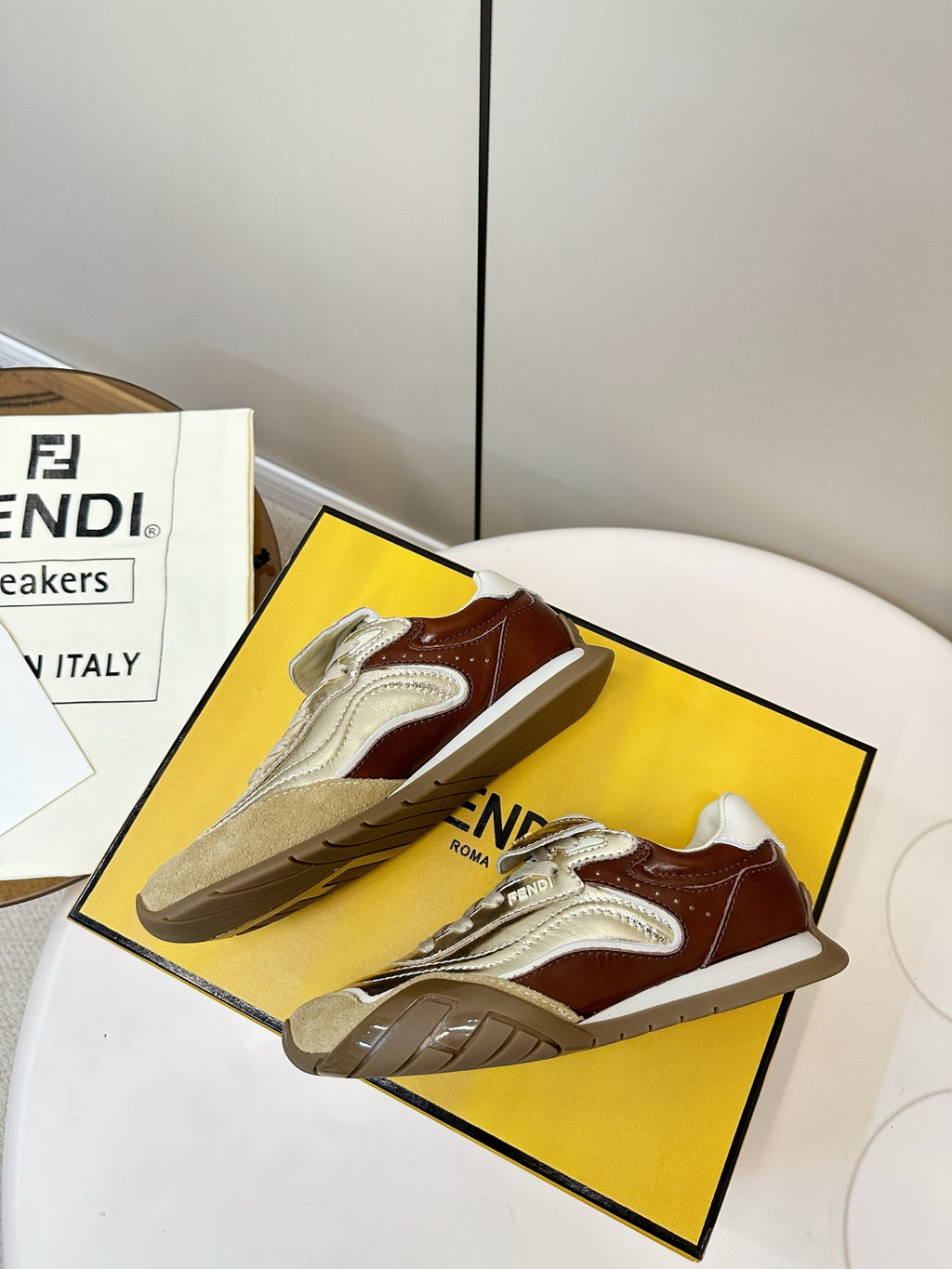 Fendi unisex sneakers on a box, metallic gold with brown accents and white laces